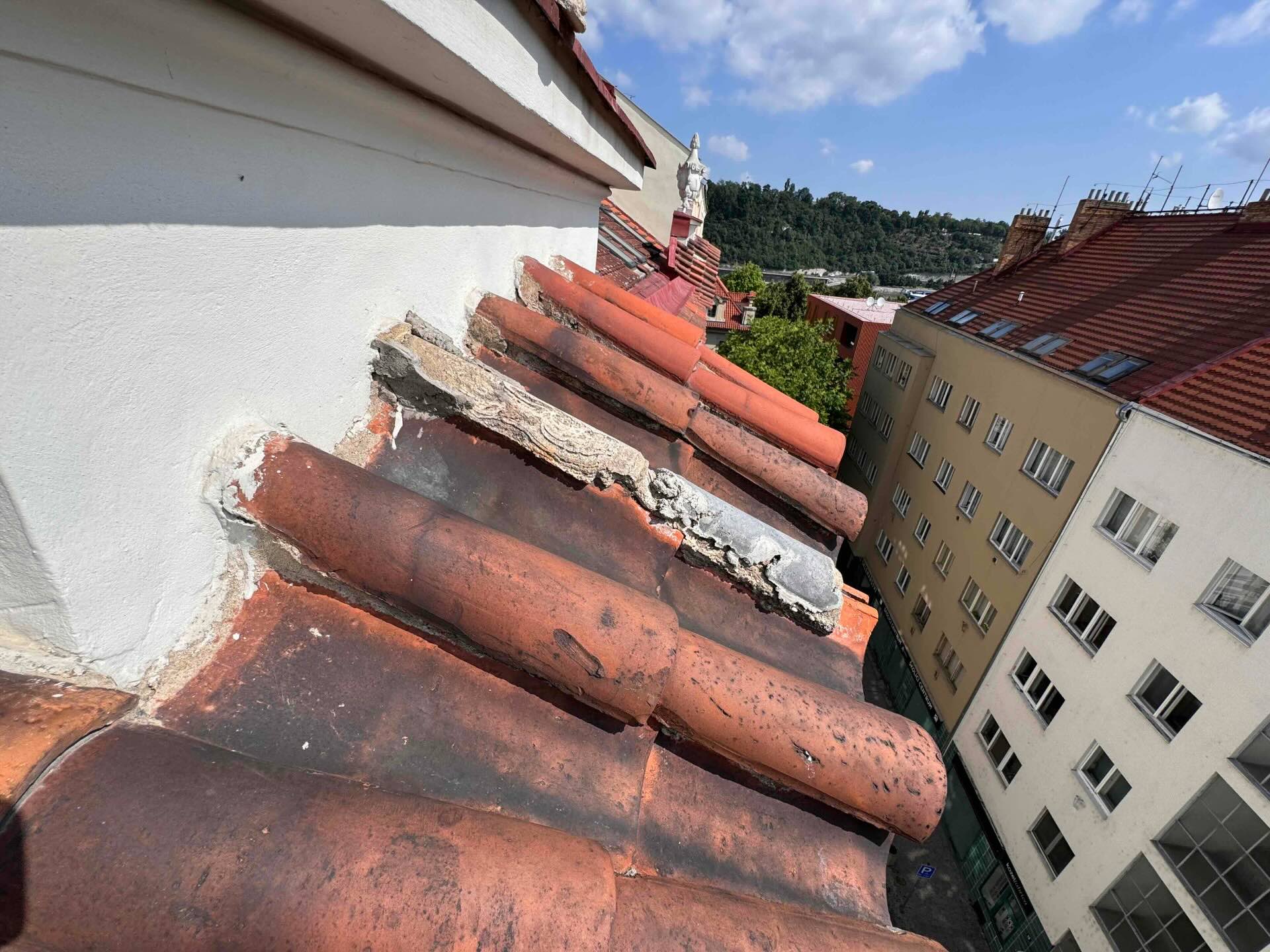 Odpadávající části krytiny nad římsou